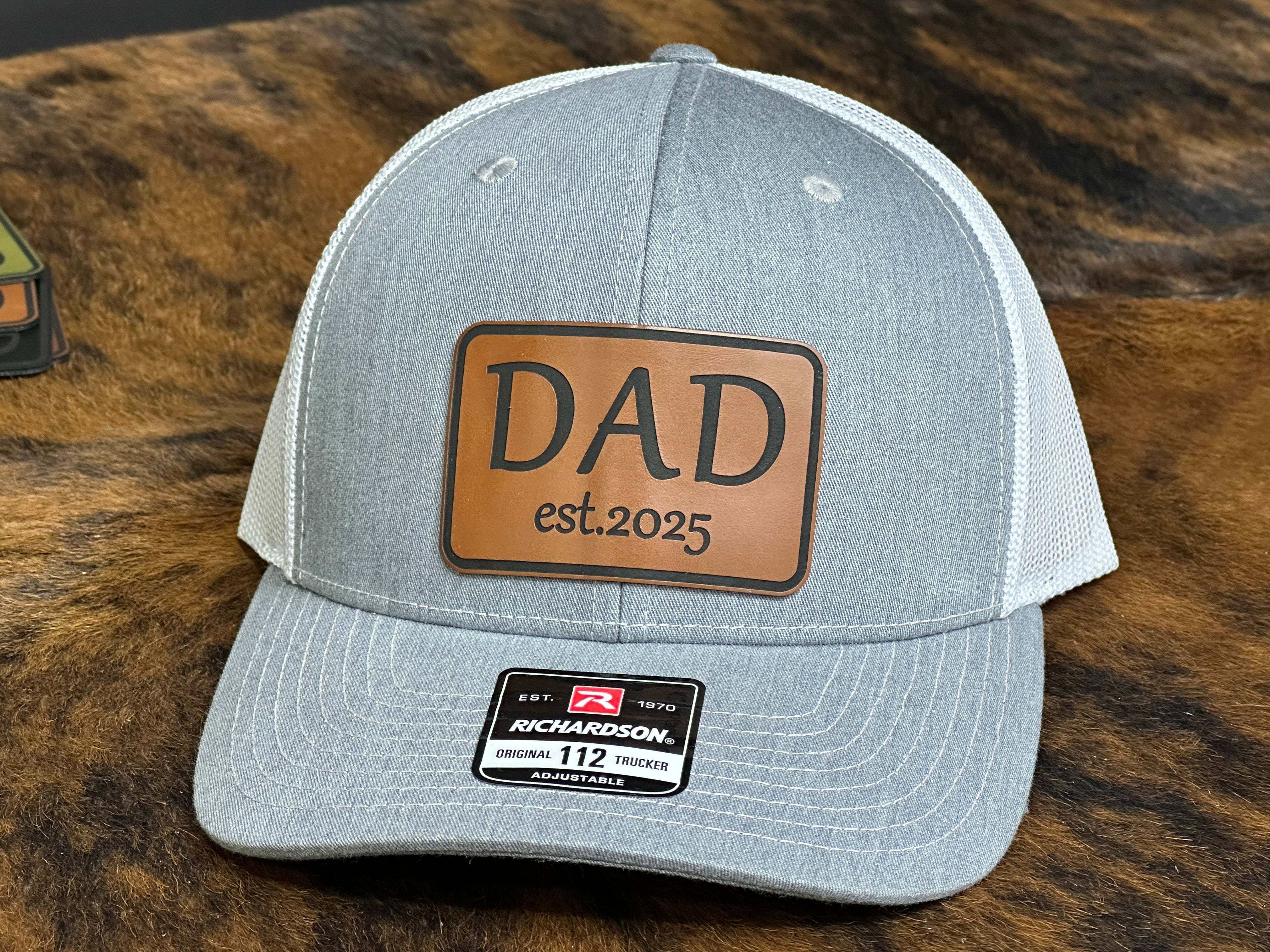 Custom dad hat with laser-engraved leatherette patch, classic trucker style, personalized with dad titles and year, perfect gift for new dads