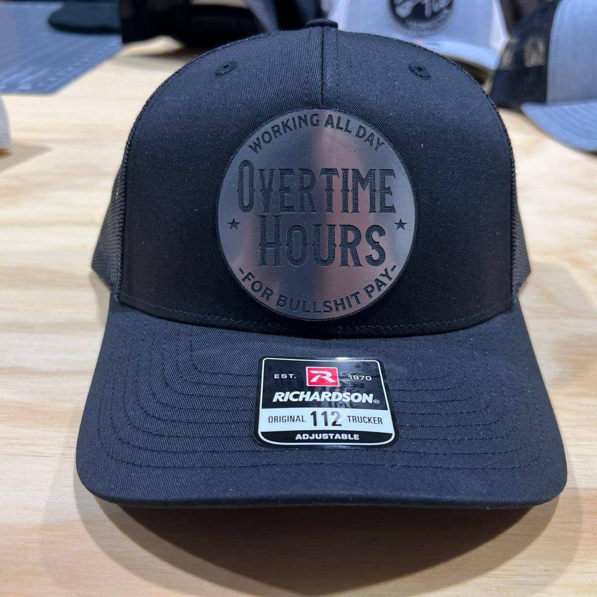 Overtime Hours Hat with leatherette patch on Richardson 112 trucker hat in black and white design